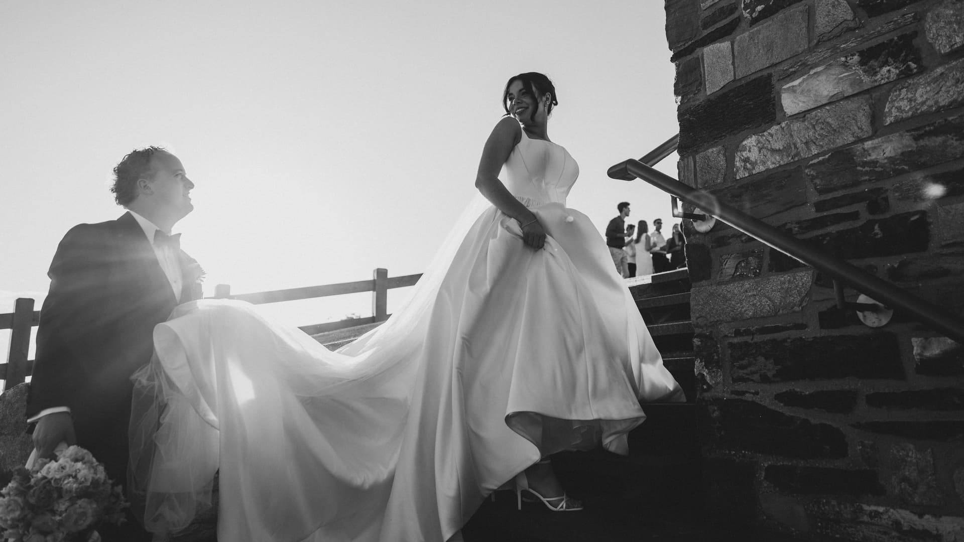 Bride on stone steps in flowing dress, black and white